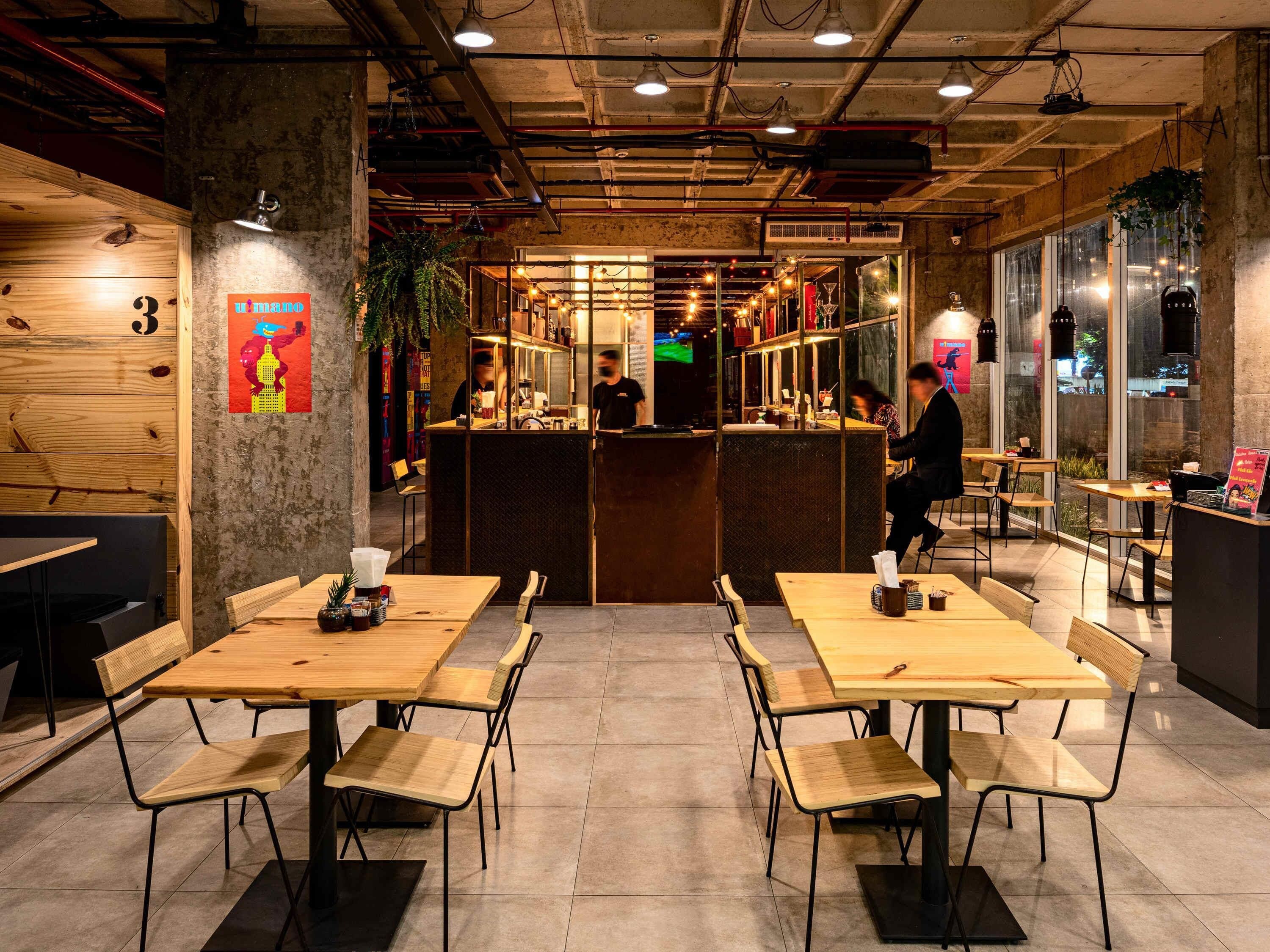 A restaurant with wooden tables and chairs, a bar area, and a view of the street outside.
