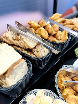 Une variété de produits de boulangerie et de pâtisserie, notamment du pain et des viennoiseries, présentés dans des paniers.