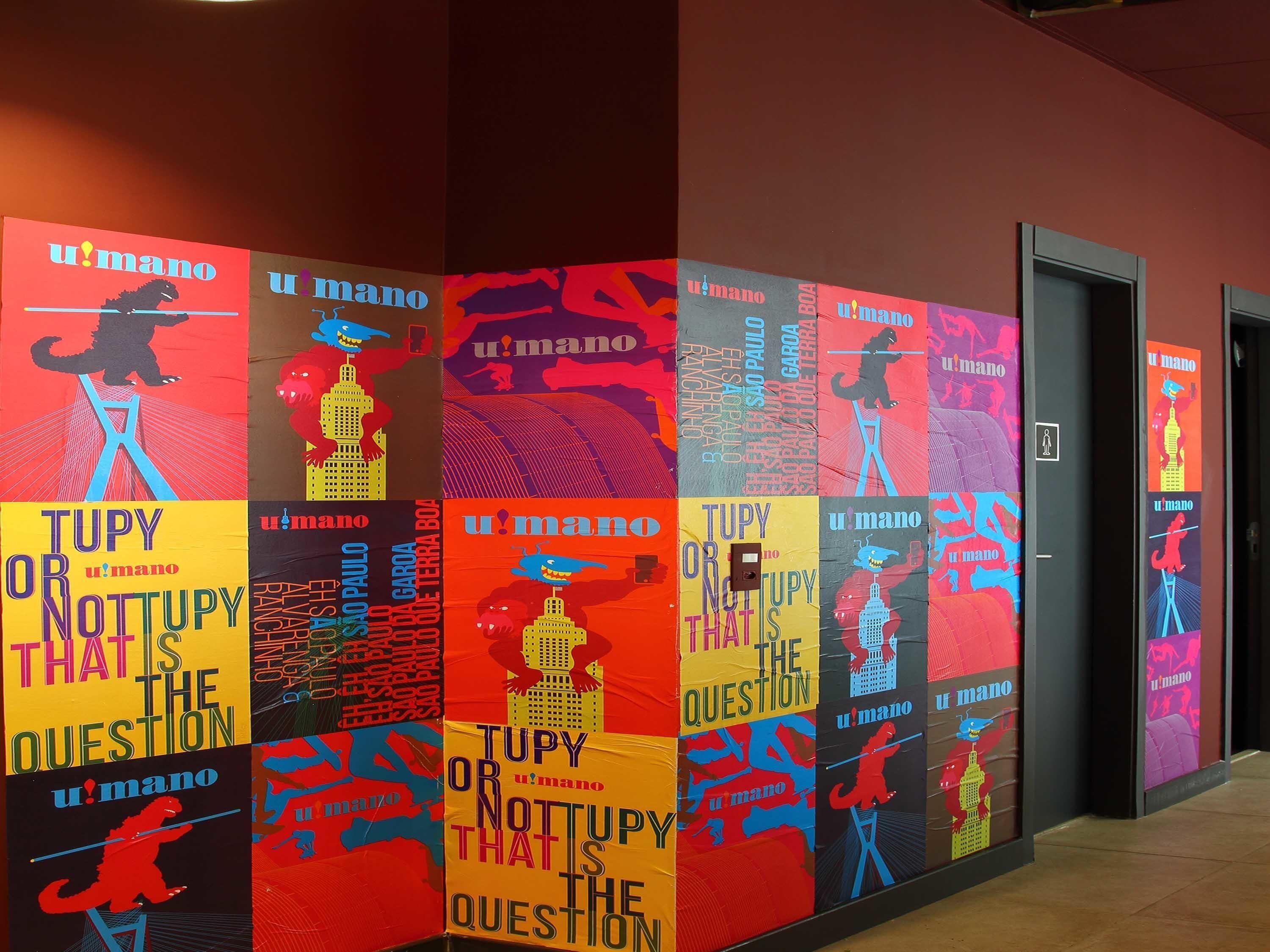 A hallway with colorful posters featuring the text "TUPY OR NOTTUPY THATS THE QUESTION" and "u'mano".