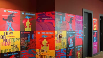 Un couloir orné d’affiches colorées sur lesquelles on peut lire les inscriptions « TUPY OU PAS TUPY, C’EST LA QUESTION » et « u’mano ».