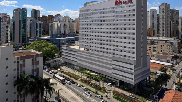 Ein modernes Hotel mit flachem Dach, mehreren Etagen und einem gut sichtbaren Schriftzug "ibis hotel".