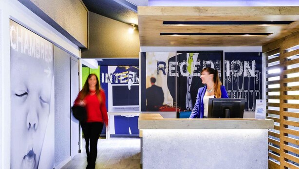 Un espace d’accueil au design moderne, un comptoir d’accueil et un mur orné d’une grande affiche.
