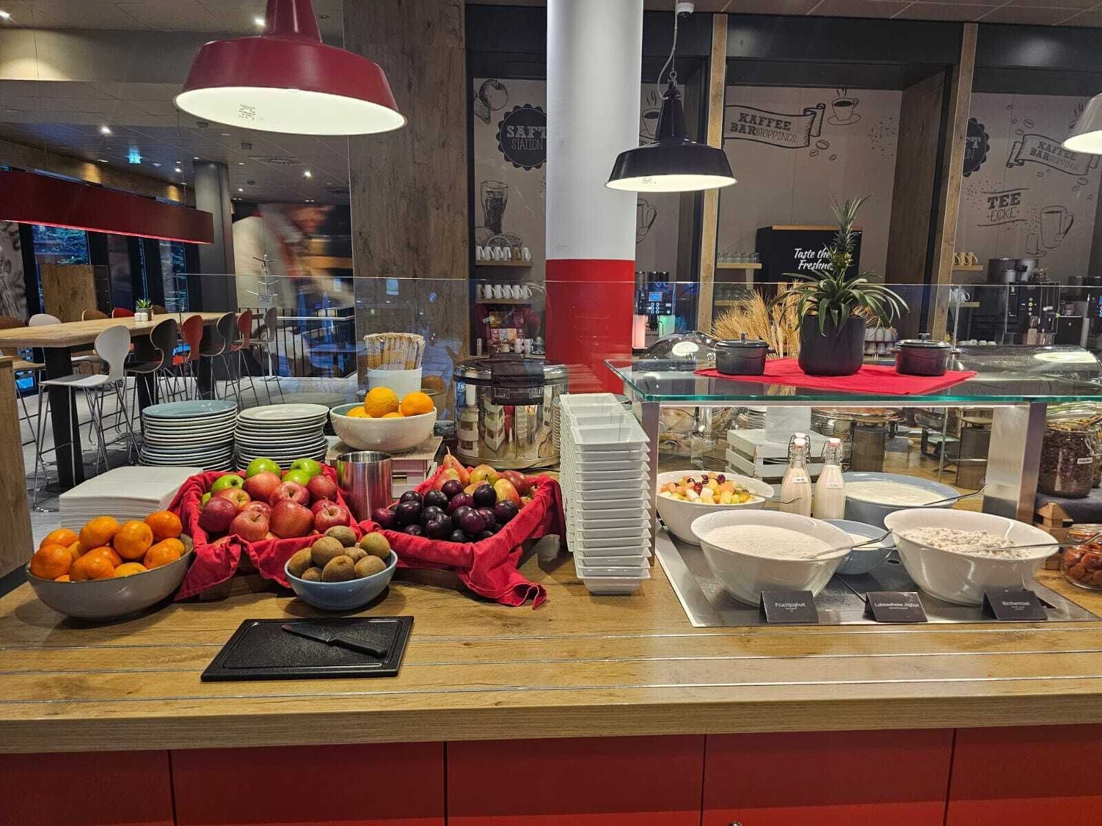A buffet setup with various fruits, bowls of cereal, and a coffee station.