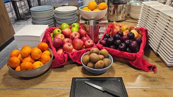 Een buffettafel met diverse soorten fruit en een mes op een snijplank.