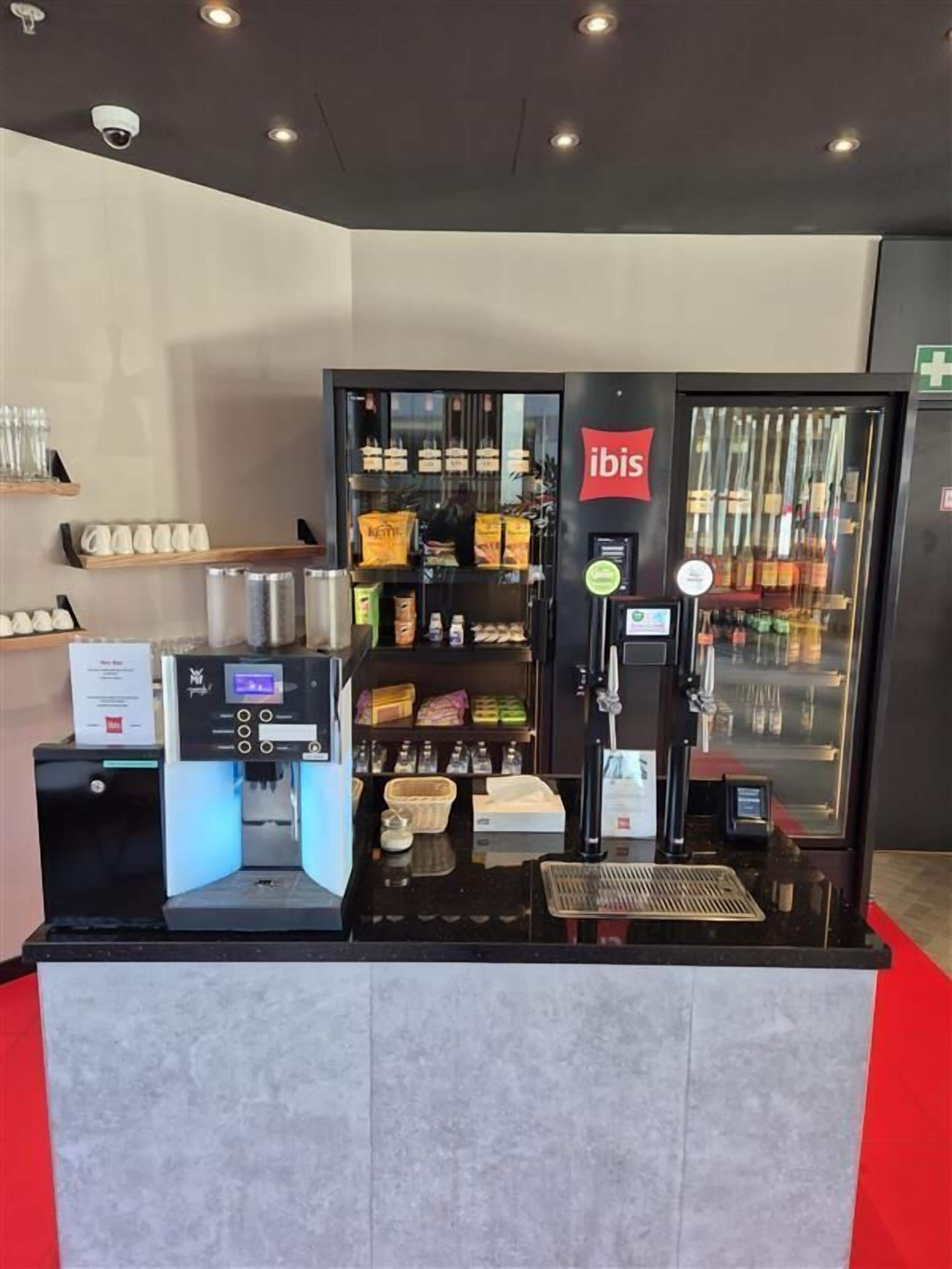 Un quiosco de autoservicio con una máquina de café, un refrigerador y una barra con un menú.