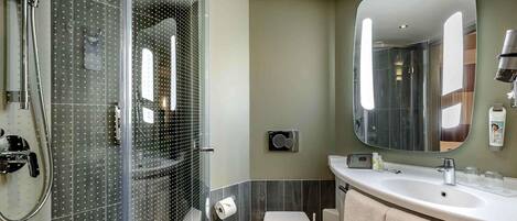 Un baño moderno con ducha de vidrio, inodoro, lavamanos y espejo.
