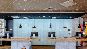 Una zona de recepción con dos mostradores, iluminación colgante moderna y suelo de baldosas.
