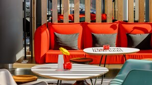 Un espacio de estar con un sofá rojo, una mesita redonda y una silla verde.