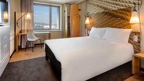 Habitación de hotel con una cama grande, un escritorio con silla, una ventana con vistas y un cabecero de diseño único.