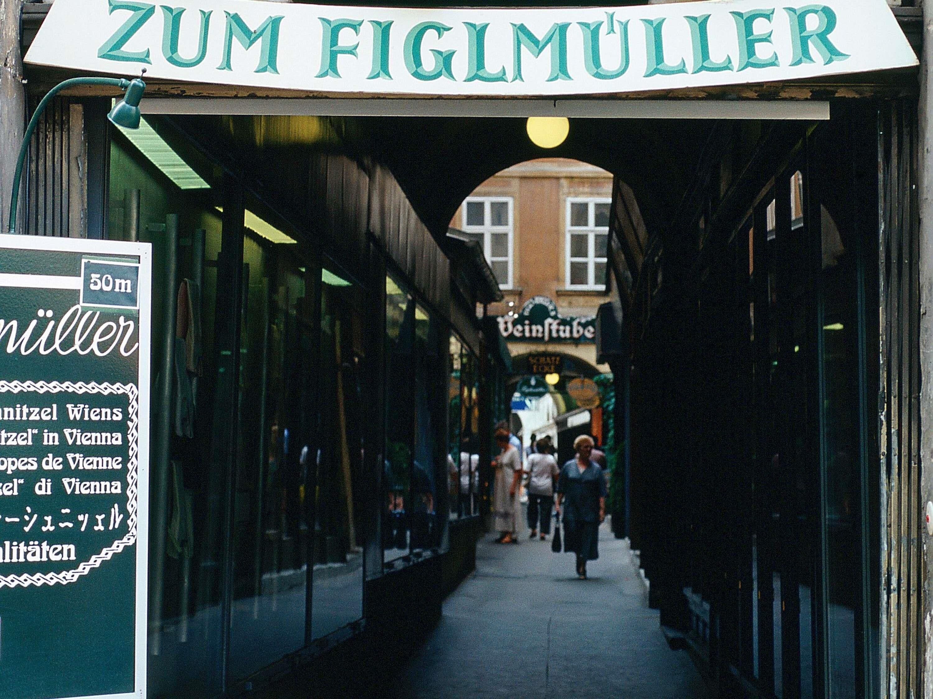 An alleyway with a sign reading 'Zum Figlmüller' and a signpost indicating '50m' distance.
