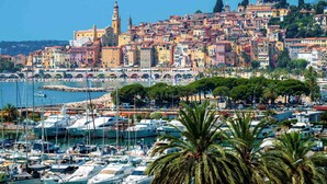 A coastal town with colorful buildings, a marina with boats, and a prominent church tower. - ibis budget Menton (Menton)