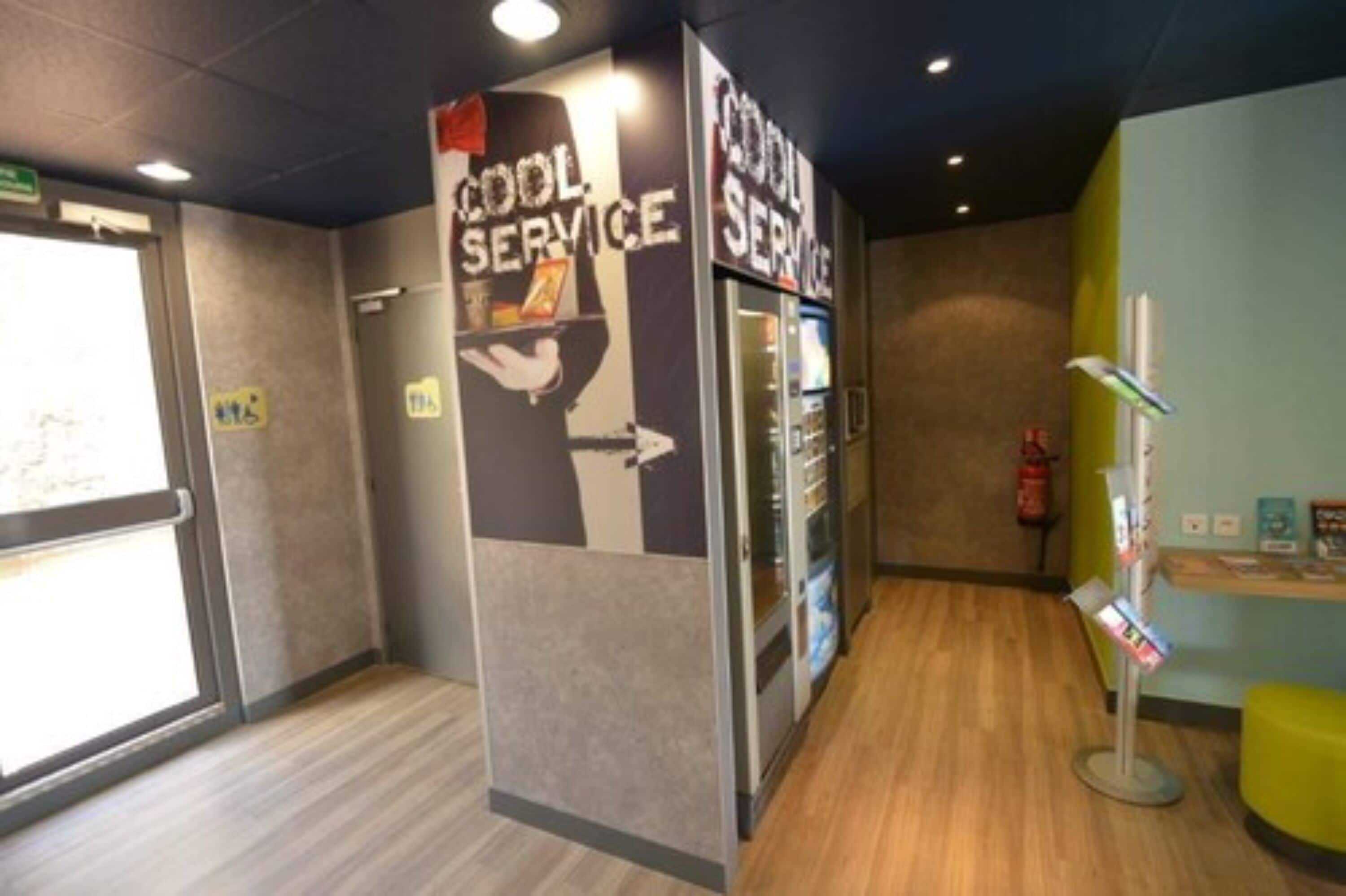 A reception area with a 'Cool Service' sign, a fire extinguisher, and a vending machine.