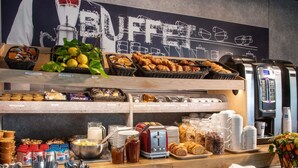 A buffet setup with various food items, utensils, and a coffee machine. - ibis budget Menton (Menton)