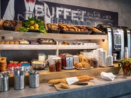 Un buffet proposant une variété de plats, d’ustensiles et une machine à café.
