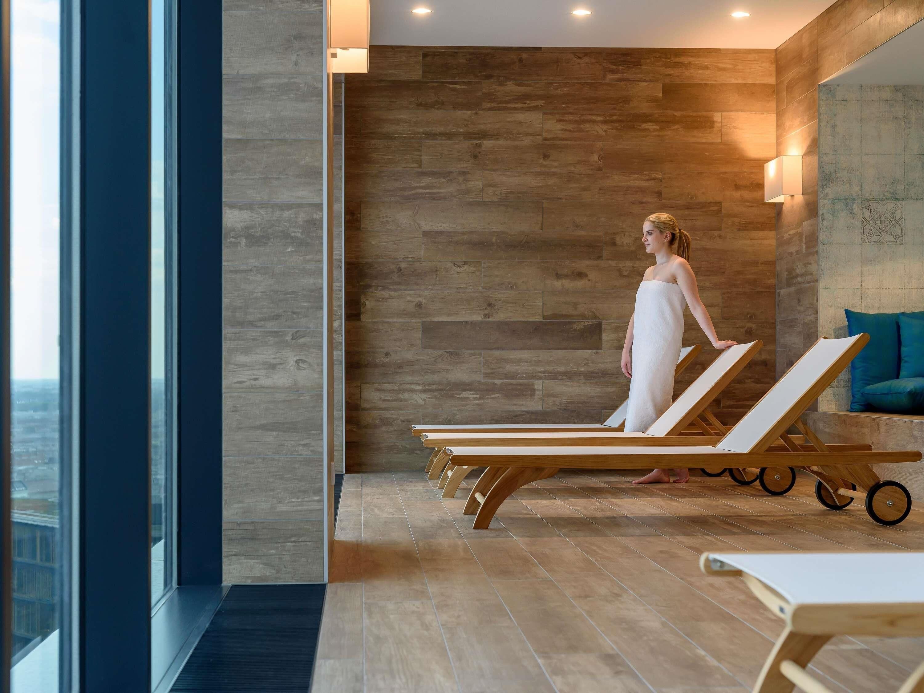 A spa area with wooden flooring, a large window, and a person in a towel.
