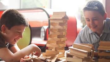 Two children playing with wooden blocks on a carpeted floor.