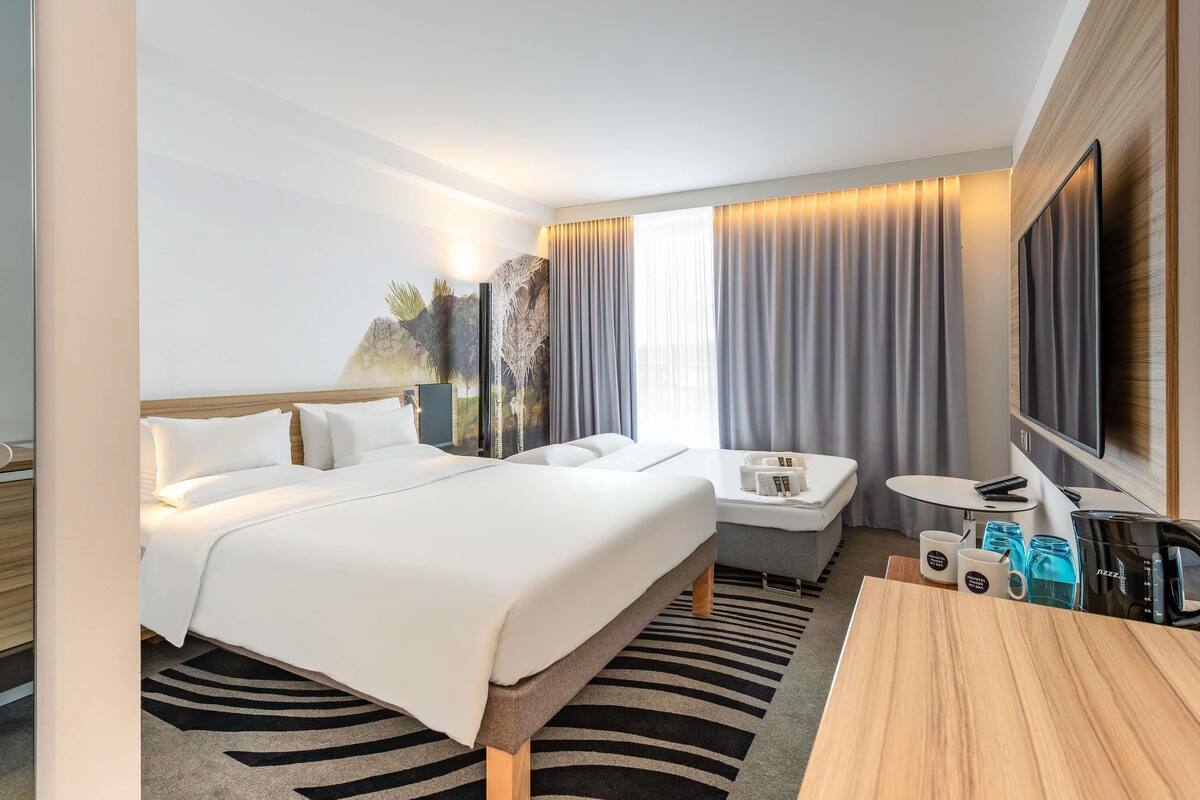 A hotel room with a large bed, a desk, a TV, and a seating area.