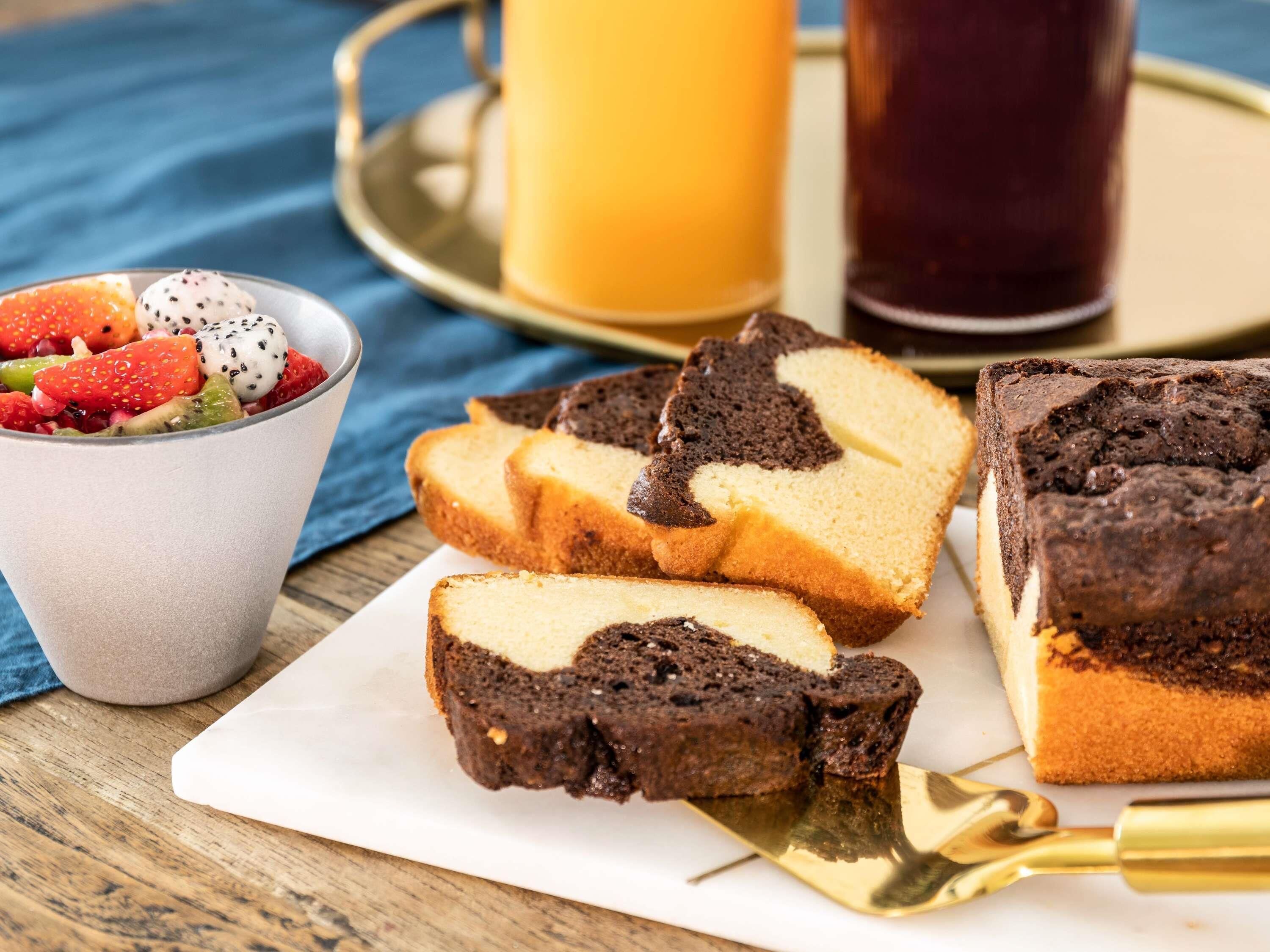 Un plateau de desserts avec des parts de gâteau et un saladier de fruits.