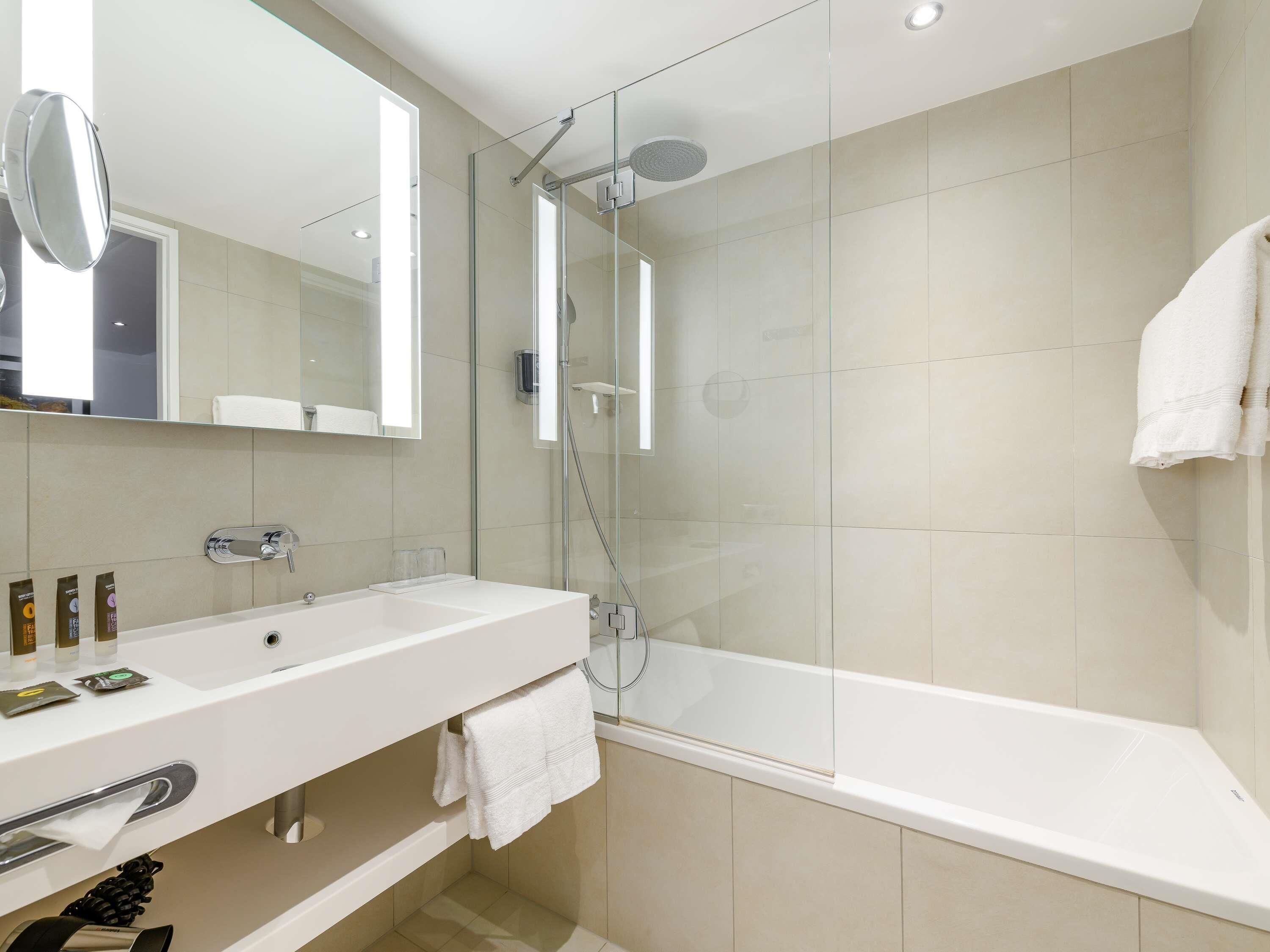 A modern bathroom with a glass-enclosed shower, a white sink, and a bathtub.