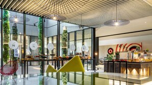 Un interior moderno con zona de comedor de vidrio, techo de madera y un mostrador de buffet con comida y bebidas.