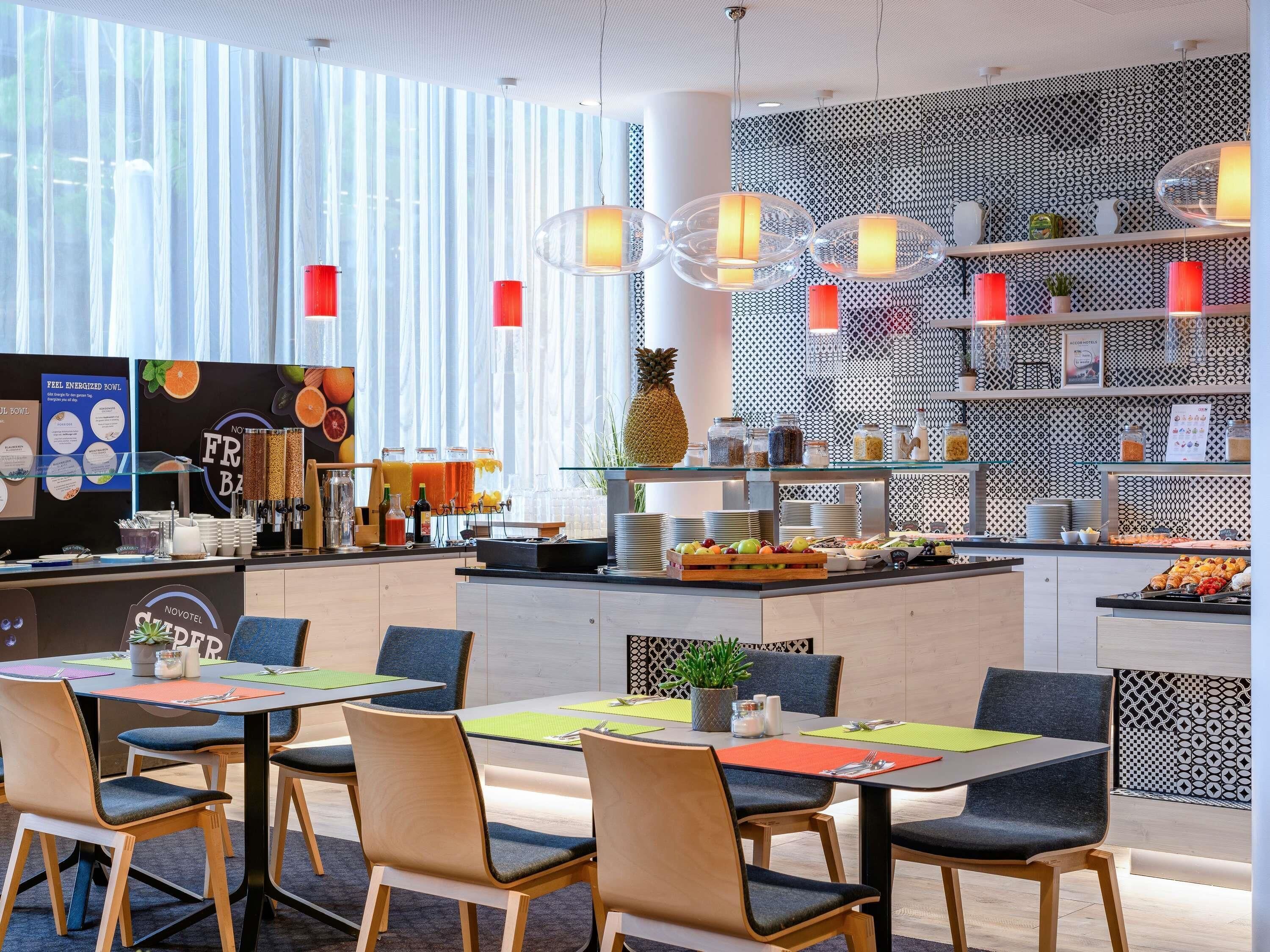 A modern hotel breakfast area with a buffet, seating arrangements, and a patterned wall.