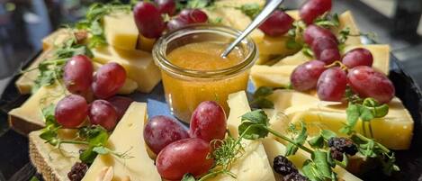 A cheese platter with grapes and nuts on a black plate.