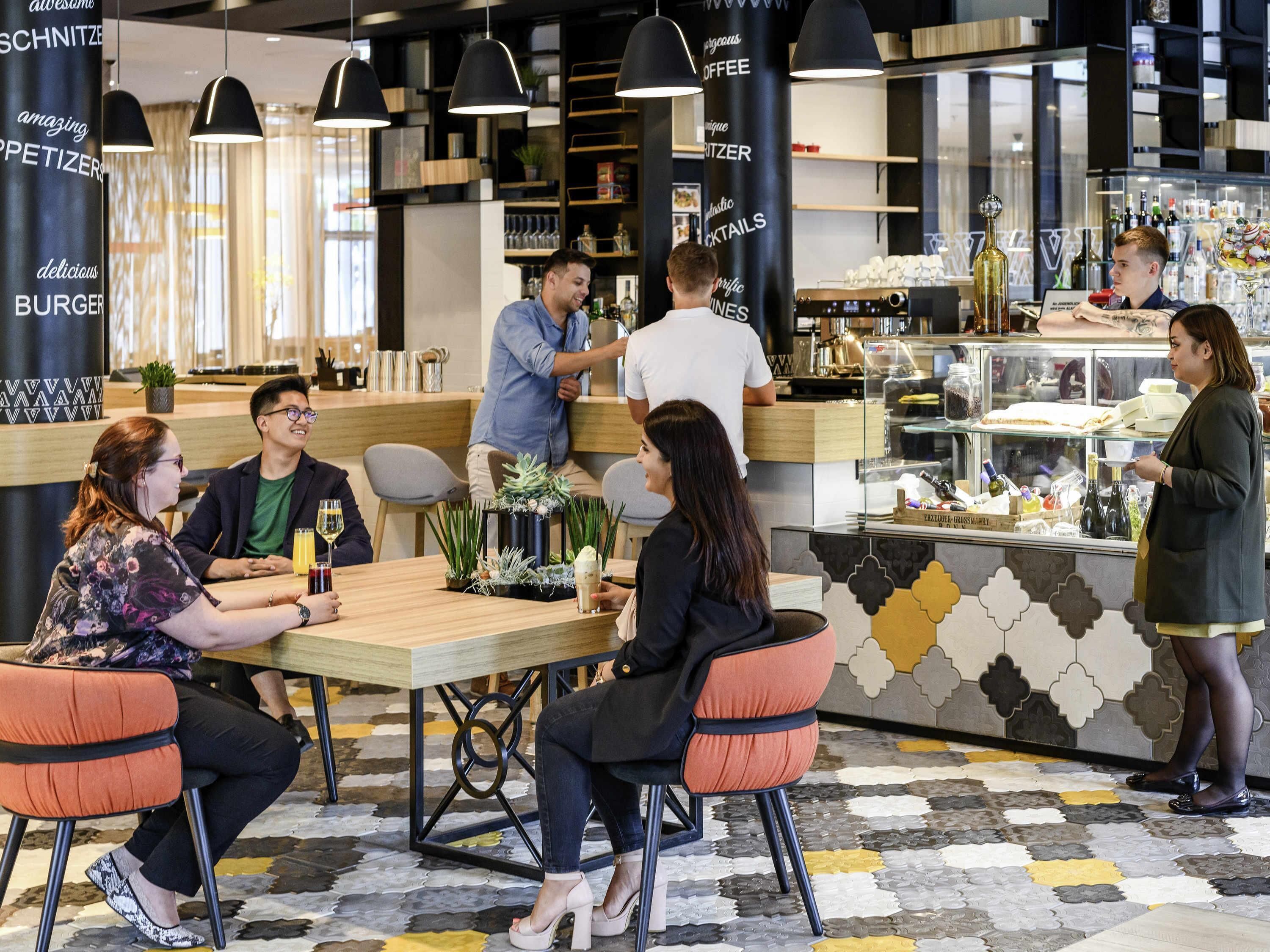 Un café moderno con mesas, sillas, una barra y un mostrador con personal.