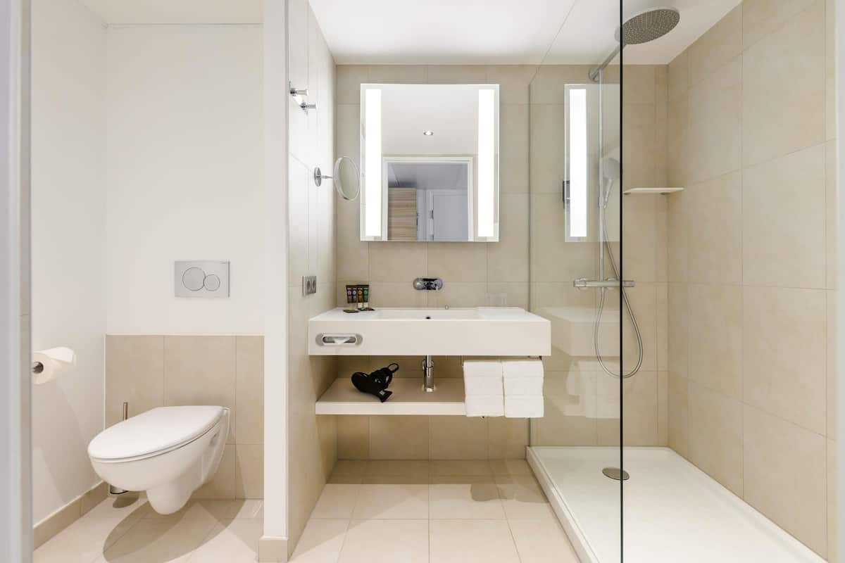 Un baño moderno con inodoro, lavamanos y ducha.