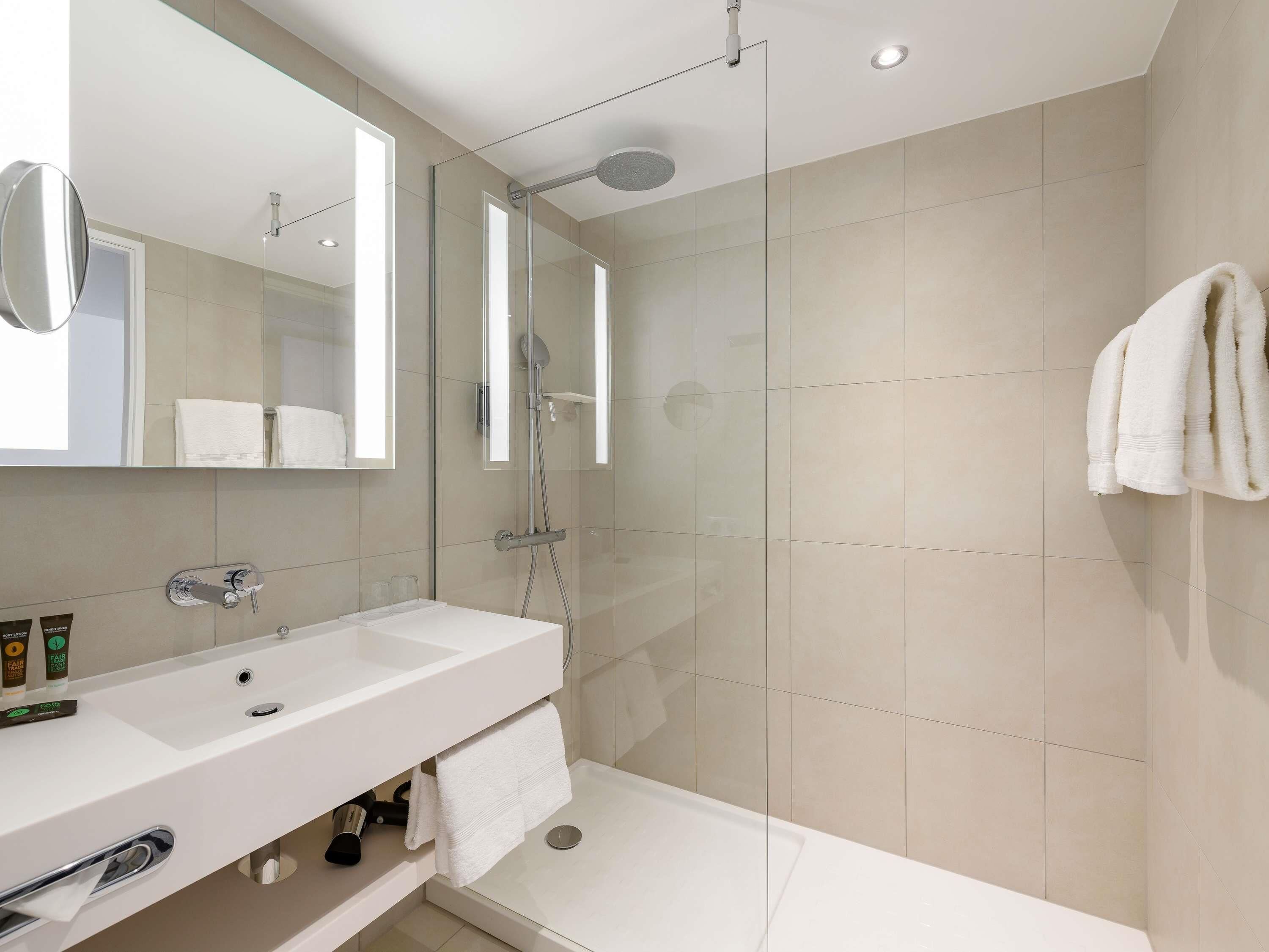 A modern bathroom with a glass-enclosed shower, a white sink, and a mirror.