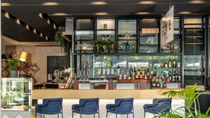Zona de bar con mostrador, taburetes y estantes llenos de botellas.