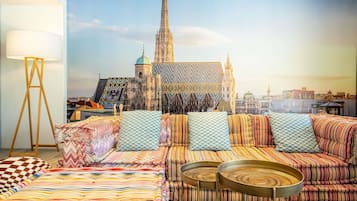 Una habitación con una cama grande, un sofá, dos mesas redondas y una lámpara de pie.