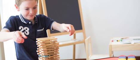 A child playing with wooden blocks and a toy car on a table.