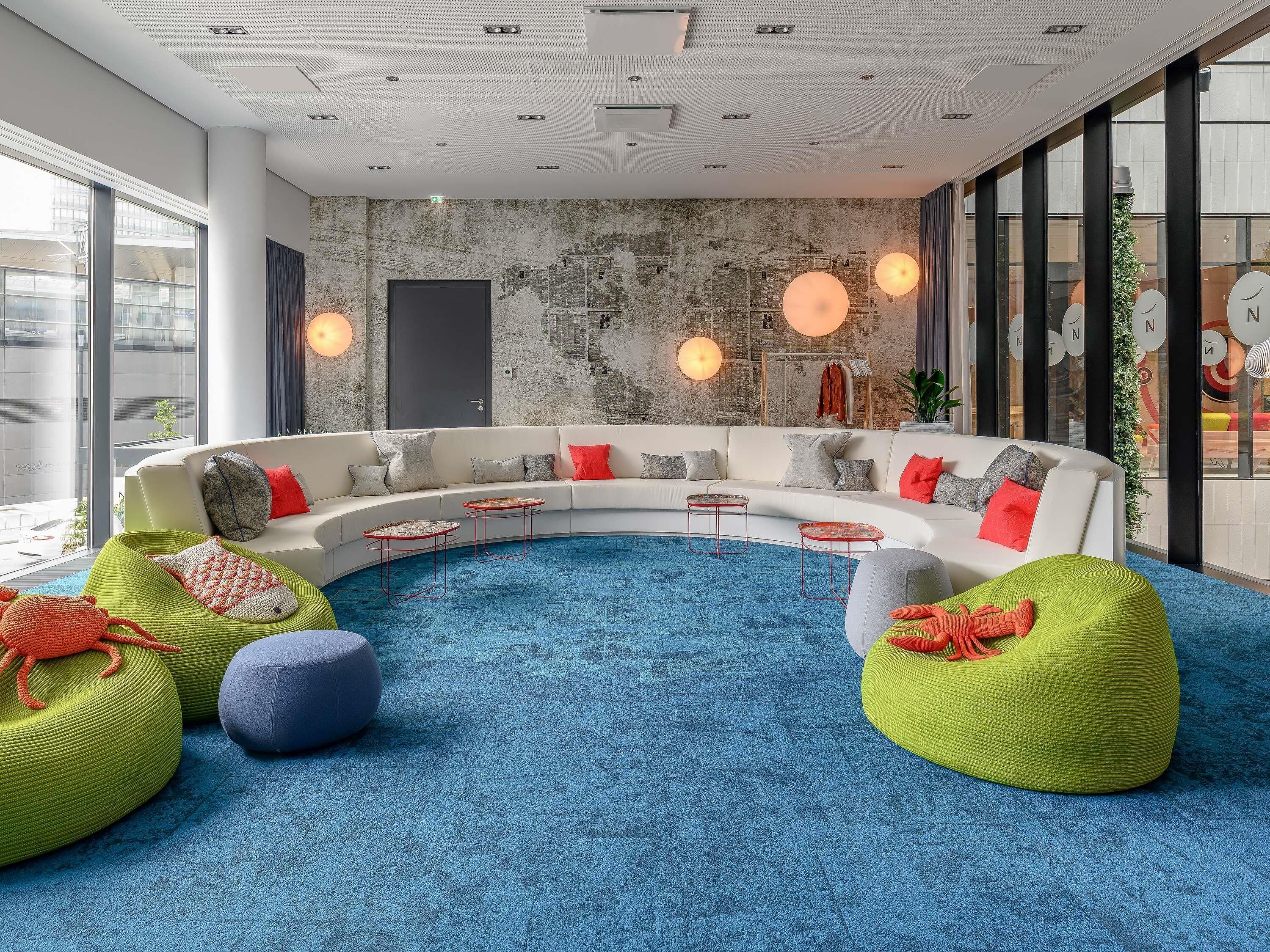 A modern interior with a curved sofa, round tables, and green bean bags.