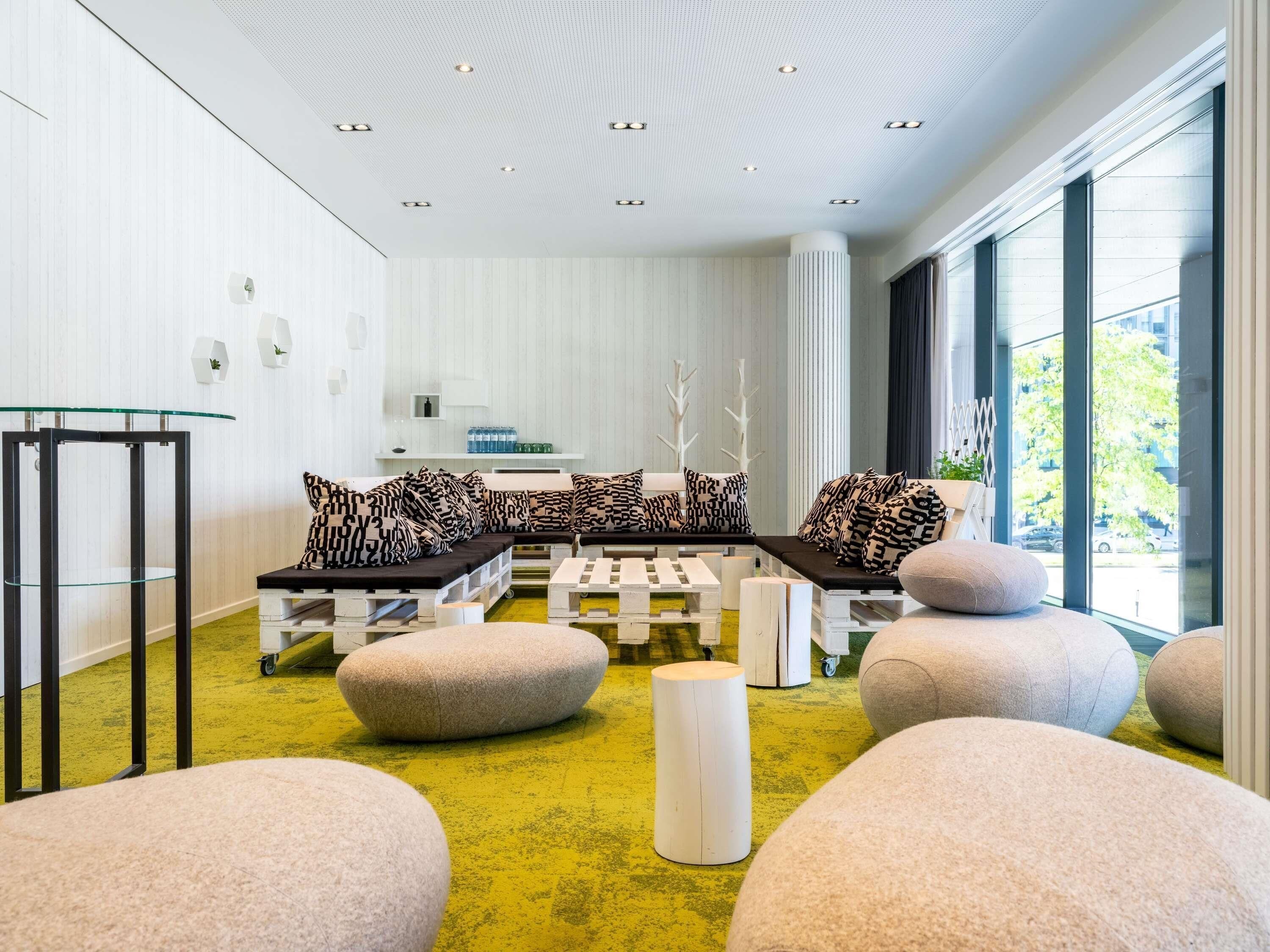Um interior moderno com área de estar, mesa de vidro e vista através de grandes janelas.