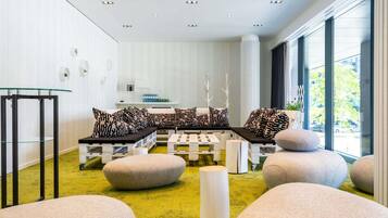 Um interior moderno com área de estar, mesa de vidro e vista através de grandes janelas.