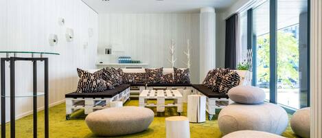 Un interior moderno con una zona de estar, una mesa de vidrio y vistas amplias a través de grandes ventanales.