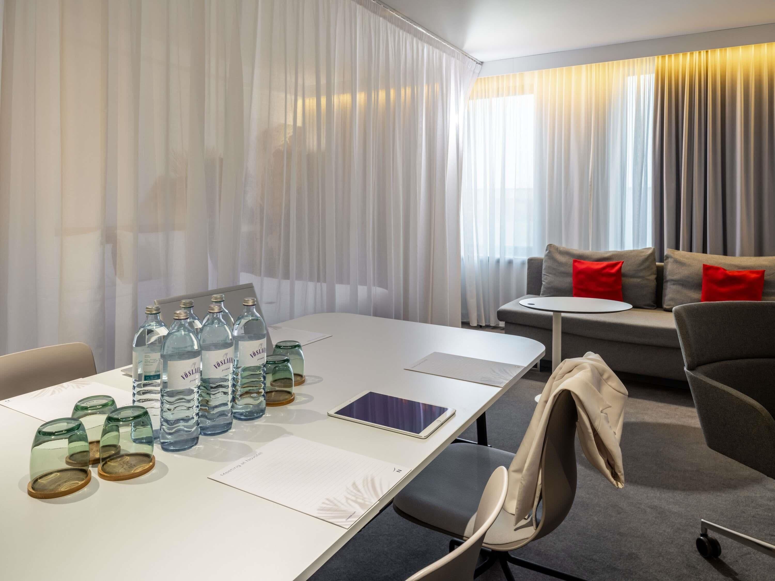 A hotel room with a dining table, chairs, a sofa, and a small round table.