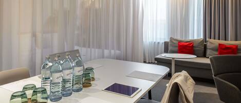 Una habitación de hotel con una mesa de comedor, sillas, un sofá y una pequeña mesa redonda.