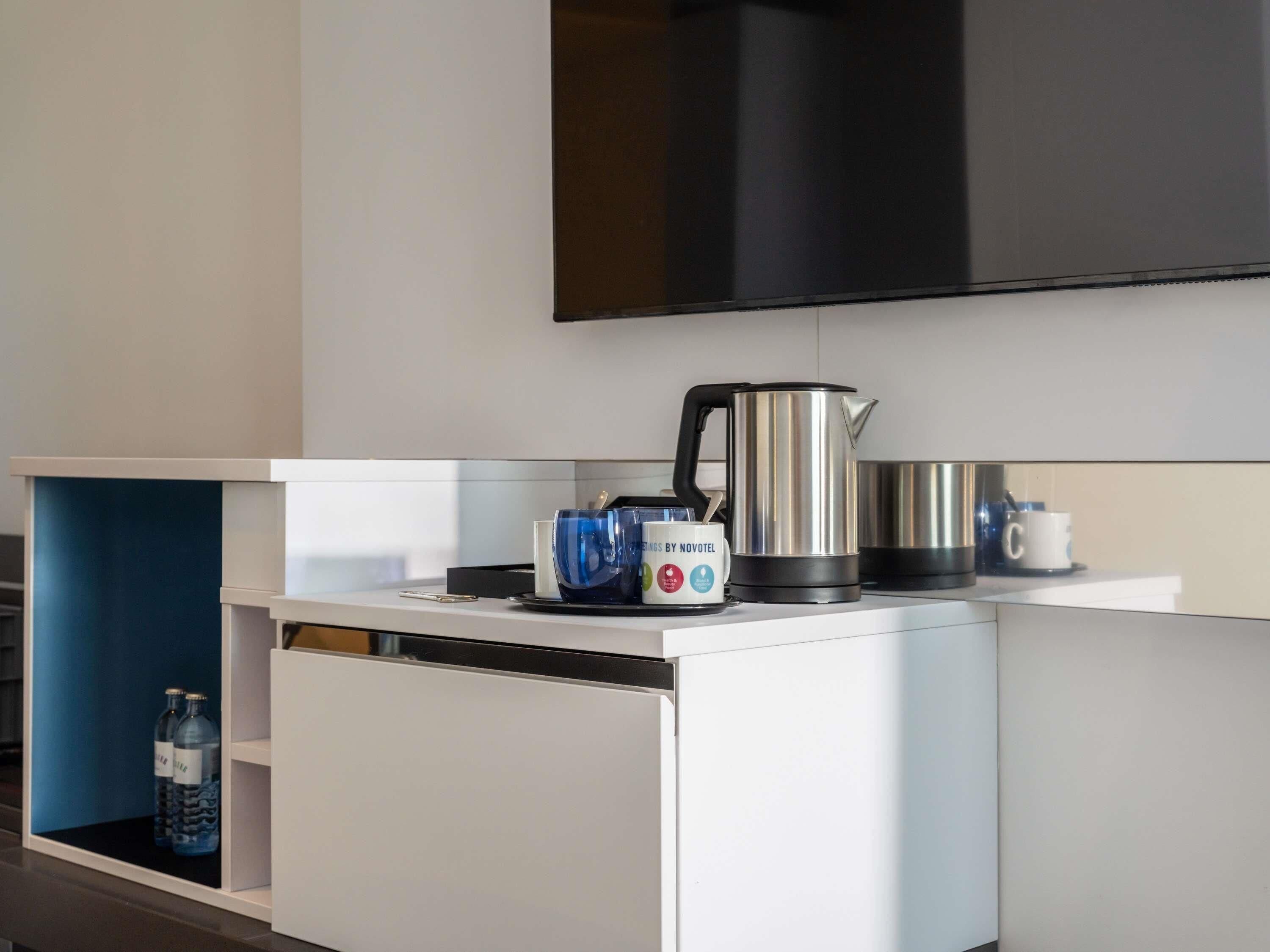 Een moderne keuken met een flatscreen televisie, een waterkoker, een koffiezetapparaat en een waterdispenser.