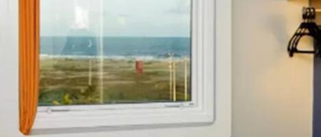A room with a large window overlooking a grassy area and a body of water.