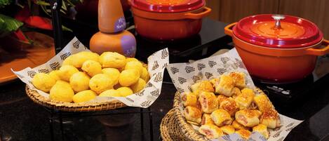 A buffet table with baskets of lemon balls and ham and cheese rolls.