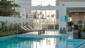 A swimming pool with lounge chairs and potted plants.