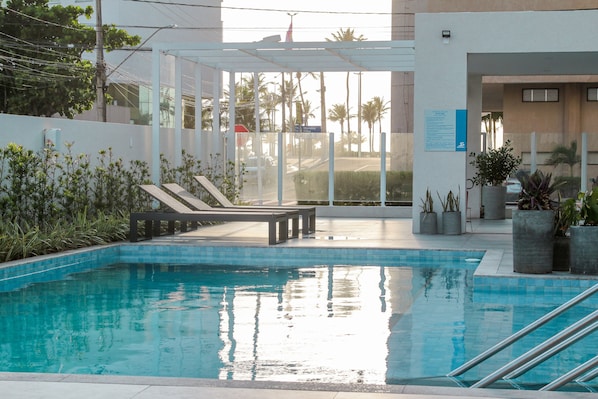 Una piscina con sillas de descanso y plantas en macetas.
