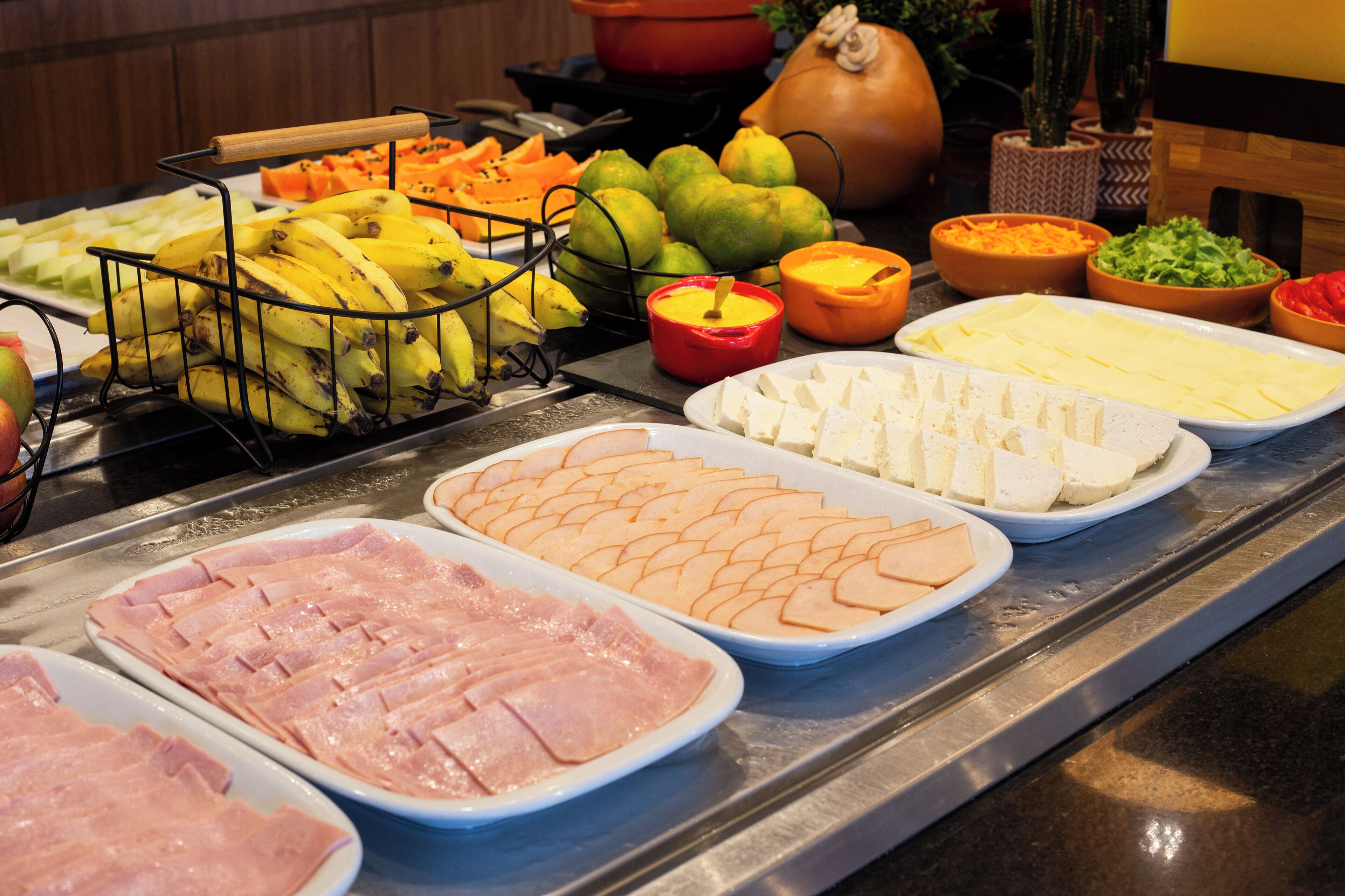 A buffet with various food items including fruits, cheeses, and meats.