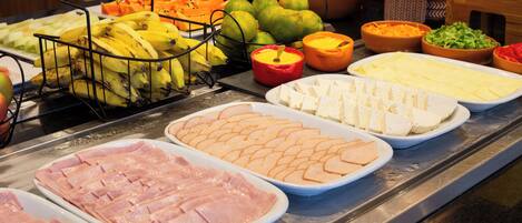 A buffet with various food items including fruits, cheeses, and meats.