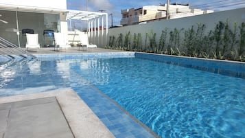 Una piscina al aire libre, sillones reclinables de piscina