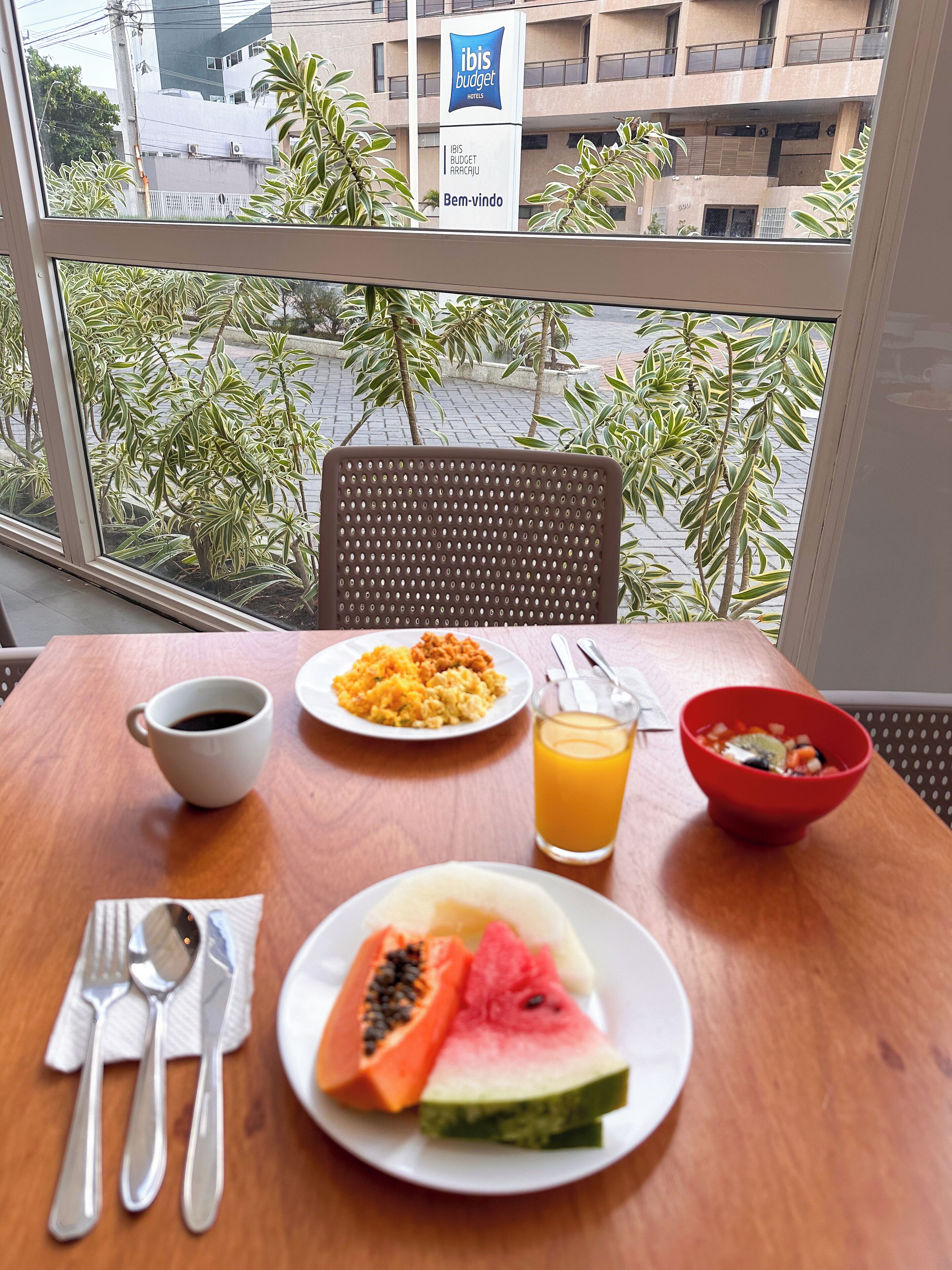 A breakfast table with plates of food, a cup of coffee, and a glass of orange juice.