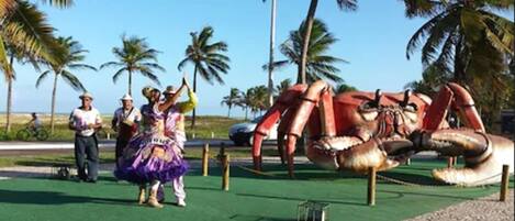 A large crab statue in a park with palm trees and a clear sky.