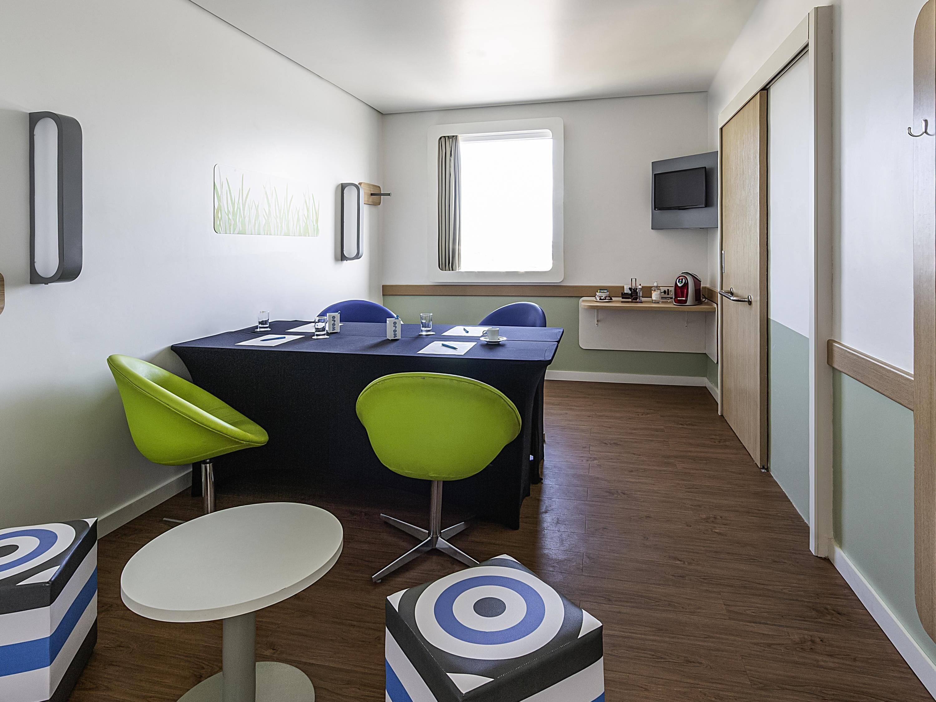 A conference room with a table, chairs, a small round table, and a television.