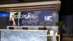 A reception desk with a modern design, a digital screen displaying information, and a sign for online check-in. - ibis budget Manaus (Manaus)
